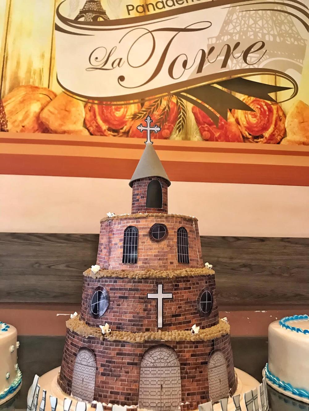 Torta en forma de iglesia frente al letrero de La Torre